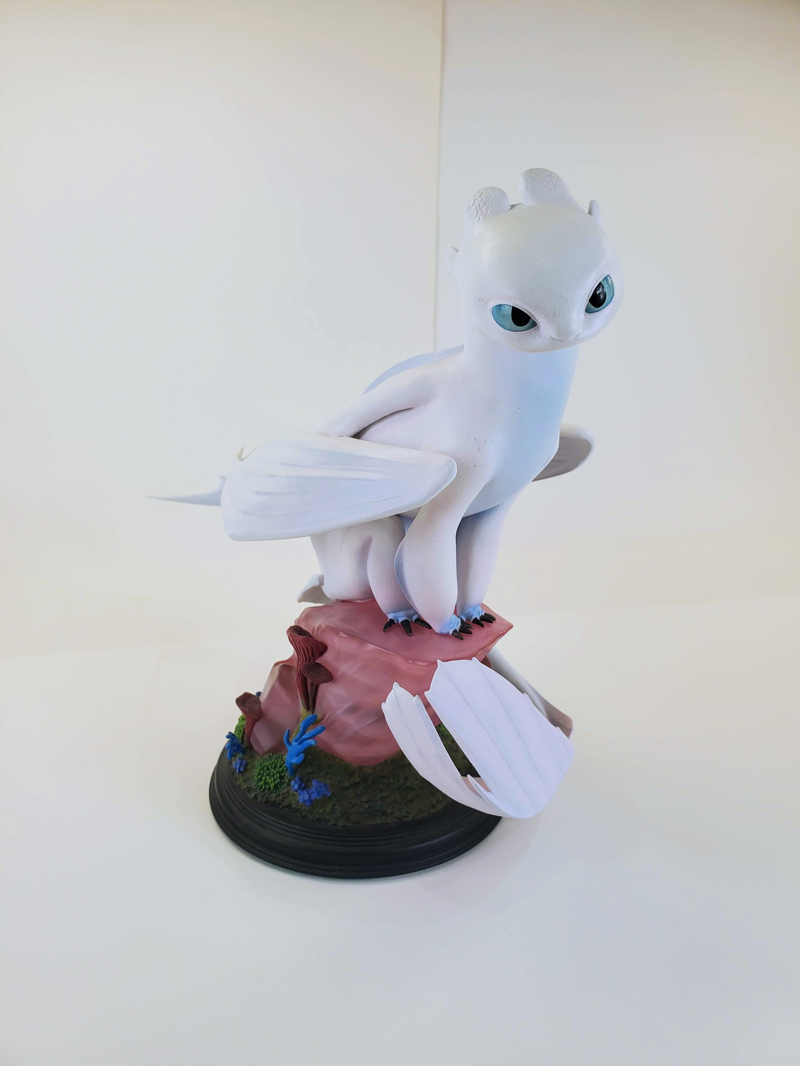 The Light Fury from How to Train Your Dragon, perched gracefully on a pink rocky base